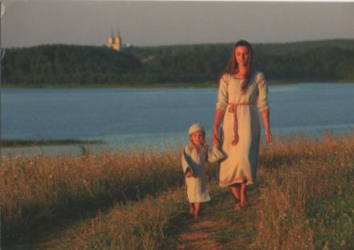 Mother and daughter walking on the bank of the river in the evening