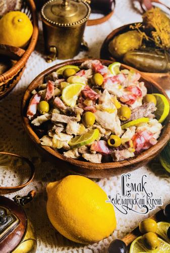 Russian salad with tuna, olives, pickled cucumbers and lemon