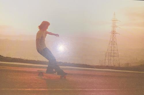 Girl rides a skateboard on the road in the morning. Photo in old color image style