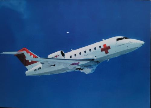 Airplane in the blue sky with a red cross on the wing