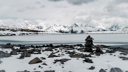 Stacked stones in the snow on the shore of the lake.