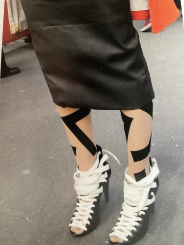 Close-up of female legs in black skirt and white sneakers.