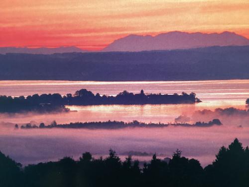Sunrise over the lake with fog and mountains in the background.