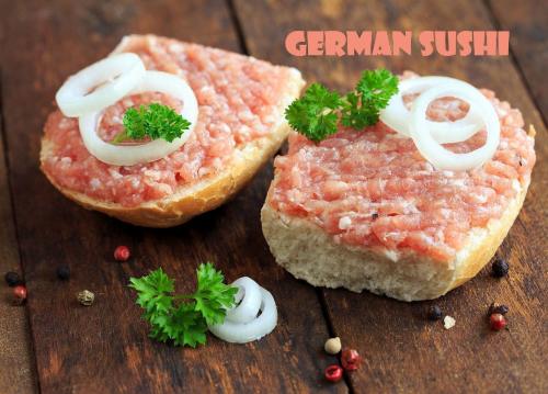 Fresh raw minced meat with onion rings and parsley on wooden background