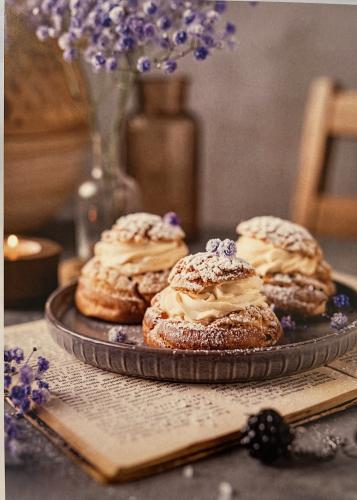 Eclairs with icing sugar and lavender flowers on a dark background