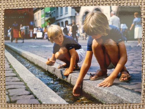 Two little boys playing in a fountain on the street of the city