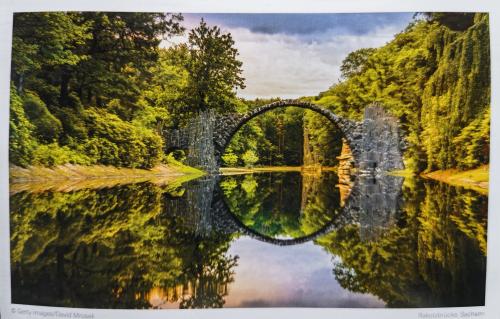 A postcard printed in the UK shows a view of a bridge over a lake