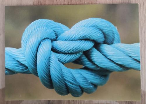 Blue rope on wooden background. Rope tied in a knot.