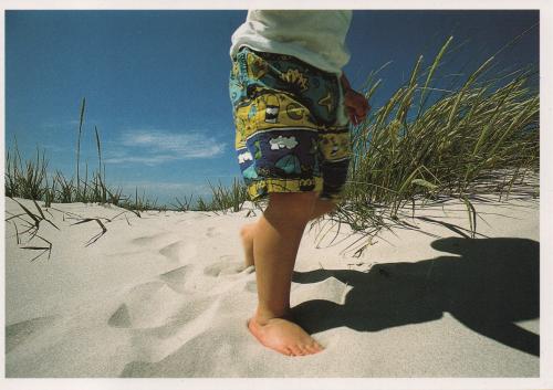 Child walking on sand dunes at the beach in San Diego, California.