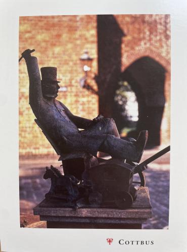 A postcard printed in Copenhagen shows a sculpture of a man sitting on a bench