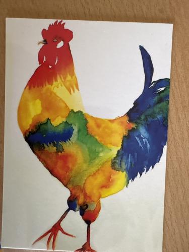 Colorful rooster on a white sheet of paper in the room