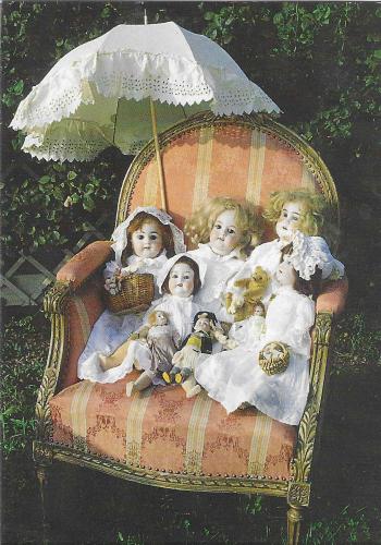 Vintage postcard with three little girls sitting in an armchair.