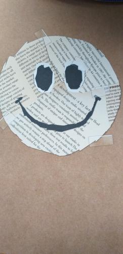 Paper face with a smile on the background of the old book.