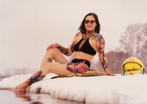 A young woman with a tattoo on her arm sitting on an ice floe