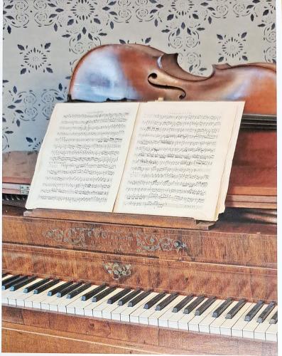 Old piano with a sheet of music and a violin on a white background