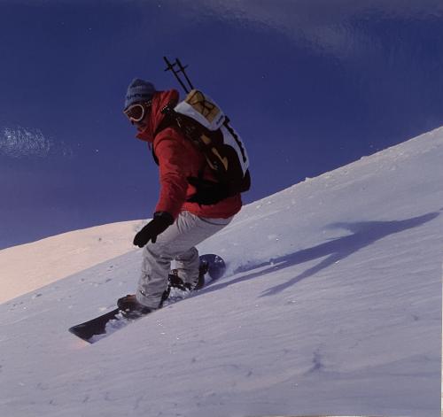 Snowboarder on top of a mountain with blue sky in the background