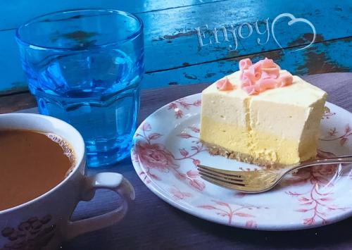 Cup of coffee and cheesecake on a wooden table with blue background