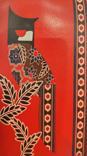 Carpenter's handcraft on a red leather bag with floral pattern