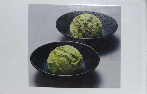 Green tea ice cream in a black bowl on a white background.