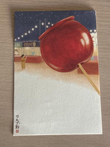 A red apple on a stick on a white sheet of paper.