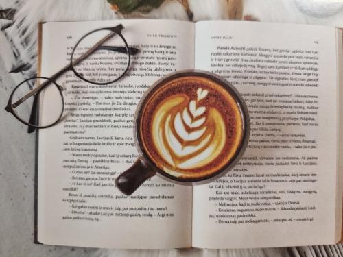 Cup of coffee with latte art on book and eyeglasses