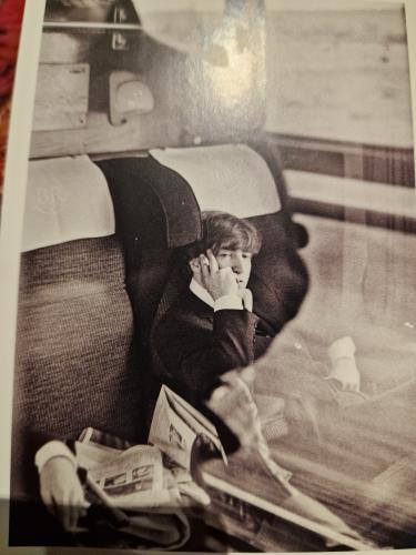 Little boy in a car seat with a newspaper in his hand.