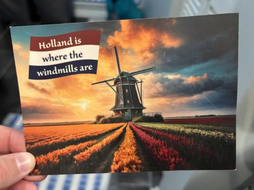 Hand holding a Dutch postcard with the image of a windmill.
