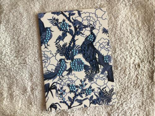 Handmade paper with blue and black patterns on a white background.