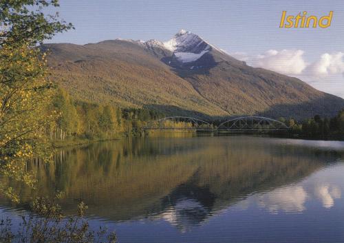 Mountains reflected in a lake with a bridge in the background.