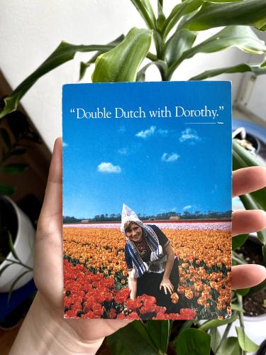 Woman hand holding a postcard in front of a flower background.
