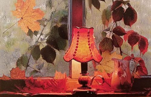 Vintage lamp with autumn leaves on the background of the window.