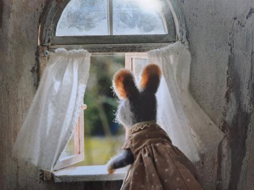 A girl in a warm sweater and gloves looks out the window.