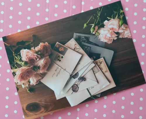 Postal envelopes and flowers on pink polka dot background.