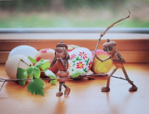 Easter decoration with eggs and wooden figures on a window sill.