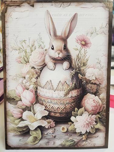 Easter egg with a rabbit and flowers on a wooden background.